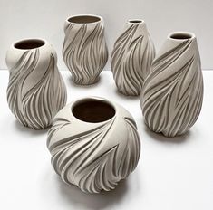 five white vases sitting on top of a table