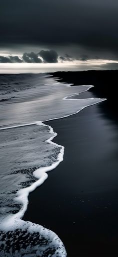 black and white photograph of the ocean with waves coming in from the shore on a cloudy day