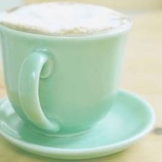 a green coffee cup sitting on top of a wooden table