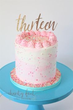 a cake with pink frosting and sprinkles on top that says thirteen