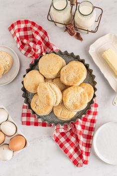 biscuits and eggs on a table with red checkered napkins next to milk bottles