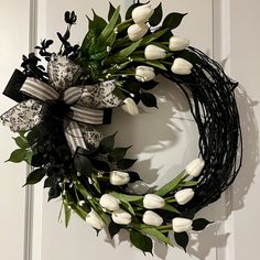 a wreath with white tulips hanging on a door