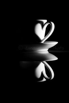 two coffee cups sitting next to each other on top of a black surface with reflections in the water