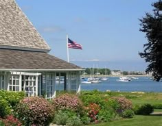 an american flag flying in front of a house by the water