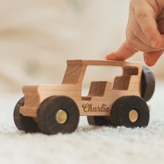 a child's hand reaching for a wooden toy car