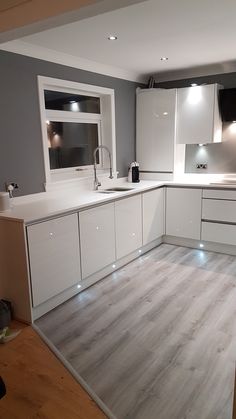 an empty kitchen with white cabinets and grey walls