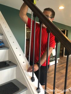 a man in red shirt and black shorts standing on stairs next to white handrail