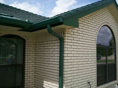 a brick building with a green roof and window on the front side, next to a white fire hydrant