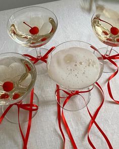 three wine glasses with red ribbons around them