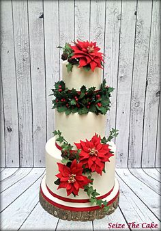 a three tiered cake decorated with poinsettis and greenery on top