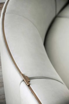 the back end of a white couch with a gold metal bar on it's arm