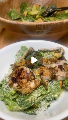 a white plate topped with lettuce and chicken next to a bowl of salad