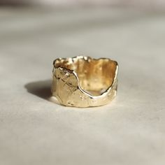 a close up of a gold ring on a table with a white surface in the background