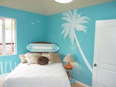 a bedroom decorated in blue and white with a palm tree painted on the wall