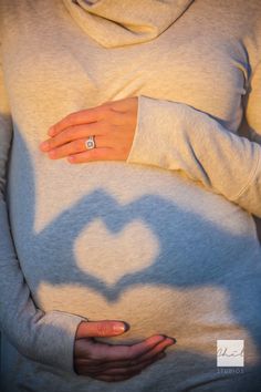 a pregnant woman's shadow cast on her stomach with a ring in the shape of a heart