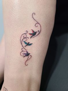 a tattoo on the leg of a woman with two birds flying over her head and swirls