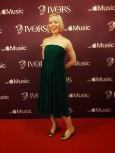 a woman standing on top of a red carpet wearing a green dress and gold shoes