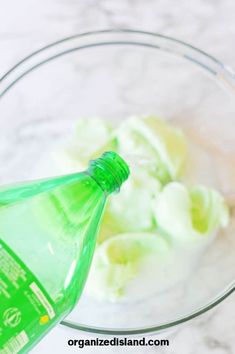 a glass bowl filled with whipped cream and a green bottle