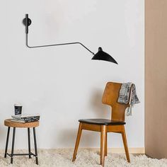 a room with a chair, table and lamp on the wall next to each other