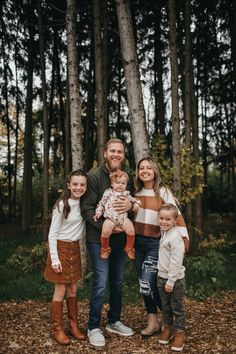 a family posing for a photo in the woods with their toddler daughter and dad