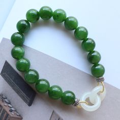 --- SPECIFICS --- 💚Materials: 100% Natural High End Green Nephrite Jade With s925 Sterling silver. Jade is from Canada, vivid green color with high quality. 💚Closure: the closure is made of 925 Sterling Silver.  💚Bracelet size: 6 -- 8 Inches 💚White Jade Inter locked circles diameter: 14mm 💚Bead Diameter: 10.0mm 8mm bead jade bracelet: https://gioiellohandcrafted.etsy.com/listing/1536648591/natural-vivid-green-jade-pearl 6mm bead jade bracelet: https://gioiellohandcrafted.etsy.com/listing/16 Elegant Jade Beaded Bracelets With Polished Beads, Handmade Round Jade Stretch Bracelet, Elegant Beaded Jade Stretch Bracelet, Elegant Hand-strung Jade Stretch Bracelet, Elegant Round Jade Stretch Bracelet, Elegant Jade Stretch Bracelet, Green Jade Bangle Beaded Bracelets, Green Jade Stretch Bracelet With Round Beads, Green Jade Beaded Bangle Bracelet