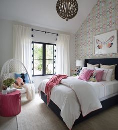 a bedroom with a large bed and colorful wallpaper on the walls, along with a hammock chair