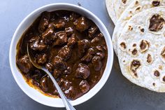 two burritos and a bowl of chili next to each other