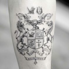 a black and white photo of a man's leg with a crest tattoo on it