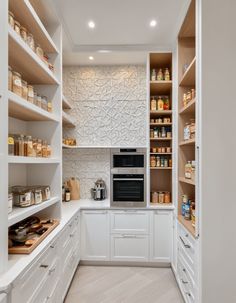 a kitchen with white cabinets and shelves filled with food