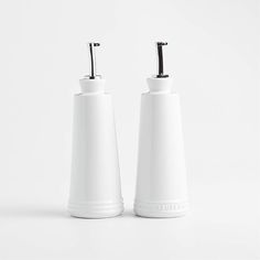 two white salt and pepper shakers sitting side by side on a white surface,