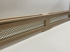 a close up of a wooden shelf on a white surface with holes in the wood