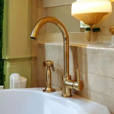 a bathroom sink with gold faucet and soap dispenser