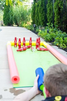 a little boy playing with an inflatable game on the ground next to some soda bottles