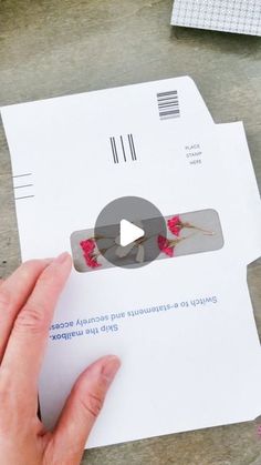 a person holding a piece of white paper with red flowers on it and an envelope in front of them