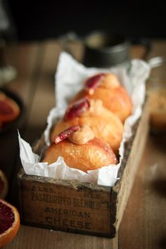 a box filled with donuts sitting on top of a table next to grapefruits