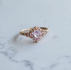 a pink diamond ring sitting on top of a marble counter