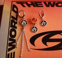 ATEEZ Anarchy Symbol earrings hoops - cuffs unisex leverback k-pop ateez logo sterling silver charm. ATTENTION: THIS LISTING IS FOR ONE EARRING (1 piece)! Also check the dimensions and material. Quantity: One (1 piece) earring NOT A PAIR. The symbol of Anarchy from my favourite Kpop group Ateez ...Atiny I see you ;)  Material: Rhodium plated (on brass) HOOP earrings lever back with STERLING SILVER 925 charm with oxidised engraving.  Dimensions: drop length: 2.6cm  sigil diameter 1cm hoop diamete Ateez Symbol Logo, Silver Hoop Jewelry For Streetwear, Silver Hoop Earrings For Streetwear, Pierced Hoop Jewelry For Streetwear, Silver Trendy Hoop Earrings For Streetwear, Minimalist Silver Earrings For Streetwear, Trendy Sterling Silver Streetwear Jewelry, Trendy Sterling Silver Jewelry For Streetwear, Ateez Earrings