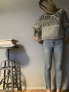 a woman standing next to a stack of books