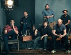 a group of men sitting next to each other in front of a photo studio light