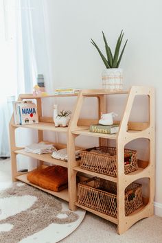 a wooden shelf with baskets on top of it next to a rug and potted plant