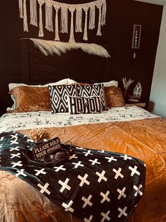 a bed with an orange comforter and two pillows on it, next to a black purse