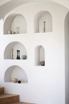 several shelves with vases on them are lined up against the wall in an otherwise white room