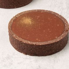 two chocolate cakes sitting next to each other on top of a white tablecloth covered surface