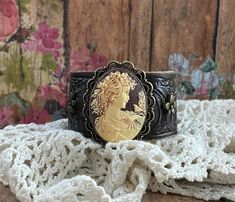 ♥*'¸.**'¨> My CAMEO COLLECTION is a treasury of beautiful traditional style cameos featuring delicate filigree settings. Each is set rustic leather for a truly unique design piece. Dress it up or downMAKE it YOUR own! ❤ This DESIGN ~ ❤ Beautifully detailed beige and brown cameo of a Victorian woman, set it in an antique bronze filigree setting ❤ Sits on dark brown hand-painted and distressed tooled leather ❤ Bronze flower rivets & small crystal rivets were added individually to the leather BRACELET SIZING INFO: My women's bracelets are approximately 8 1/2 inches end to end. I place 2 snaps at 7 and 7 3/4 inches for adjustability. jewelry for your heart & soul <-----❤---- NOTE ❤ ---> The listing photos you are seeing are of my original designs. I only change the photos when there is a signi Vintage Leather Bracelet Gift, Vintage Leather Bracelet For Gift, Gold Vintage Leather Bracelet, Vintage Gold Leather Bracelet, Vintage Bangle Cuff Bracelet, Vintage Adjustable Cuff Bracelet, Vintage Adjustable Cuff Bracelet As Fashion Accessory, Vintage Cuff Leather Bracelet Gift, Vintage Leather Cuff Bracelet