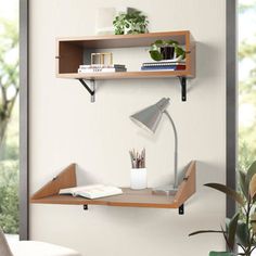 a desk with a lamp, bookshelf and other items on it next to a window