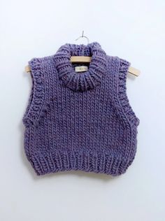 a purple knitted sweater hanging on a wooden hanger