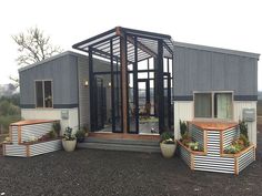 a small house made out of shipping containers with plants in the front and side windows