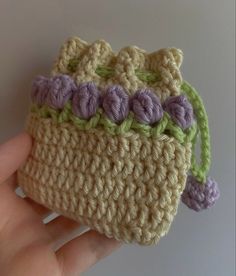 a hand holding a small crocheted purse