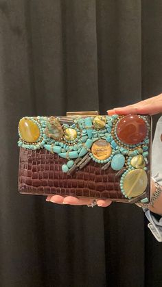 a woman is holding a purse with beads and stones on it