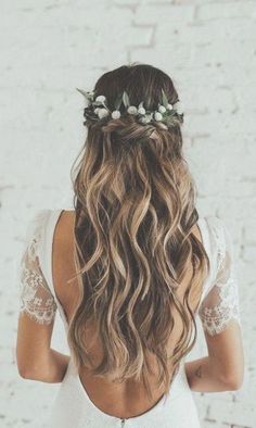 the back of a woman's head with long hair and flowers in her hair